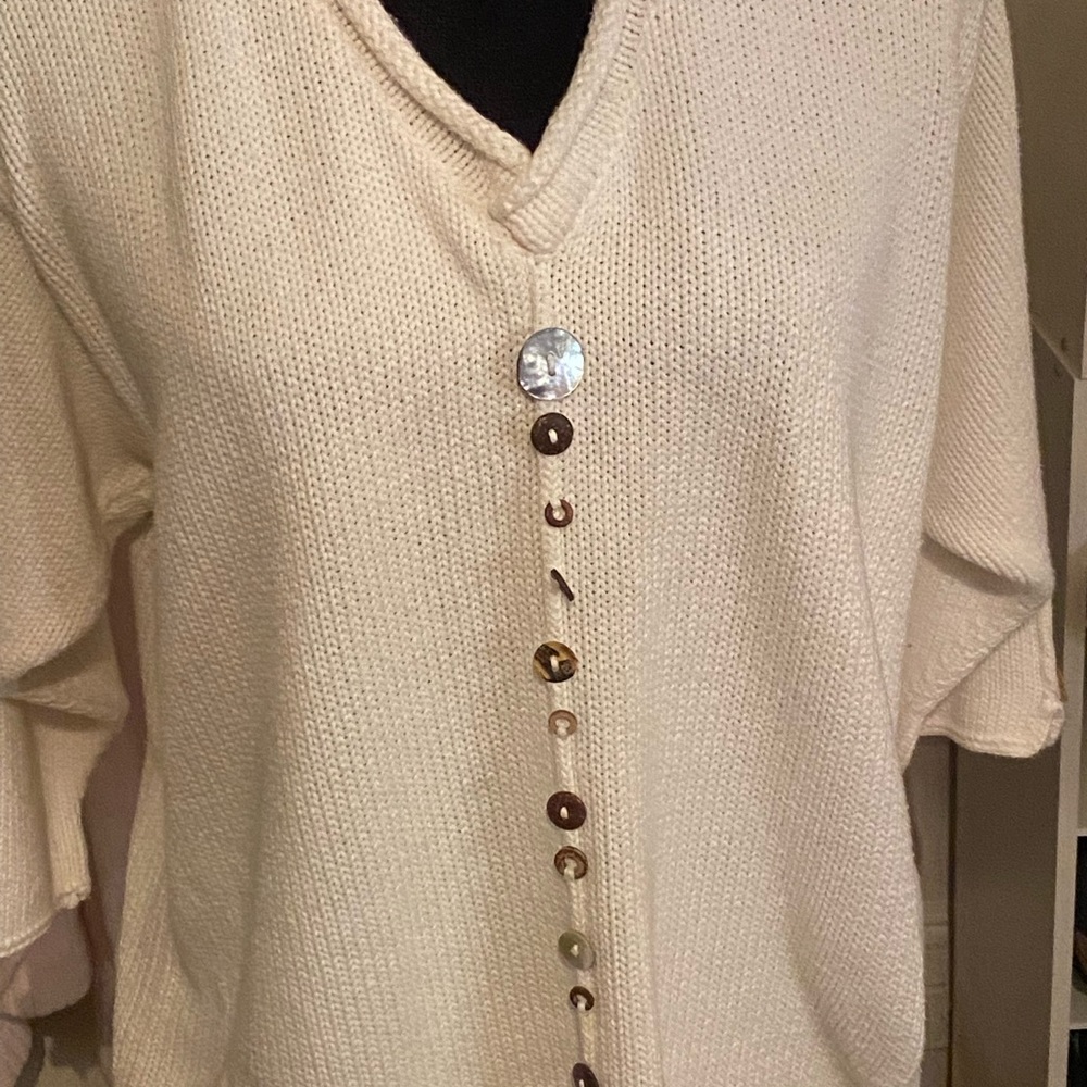 White cotton sweater with multi earth tone buttons.